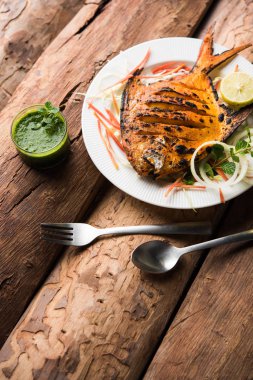 Tandır Pomfret balık kil fırında pişmiş ve limon, nane, lahana ve havuç salatası ile süslenmiş. Seçici odak