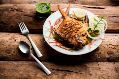 Tandır Pomfret balık kil fırında pişmiş ve limon, nane, lahana ve havuç salatası ile süslenmiş. Seçici odak