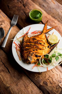 Tandır Pomfret balık kil fırında pişmiş ve limon, nane, lahana ve havuç salatası ile süslenmiş. Seçici odak