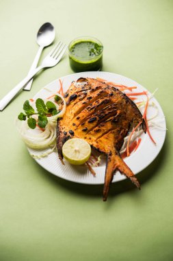 Tandır Pomfret balık kil fırında pişmiş ve limon, nane, lahana ve havuç salatası ile süslenmiş. Seçici odak