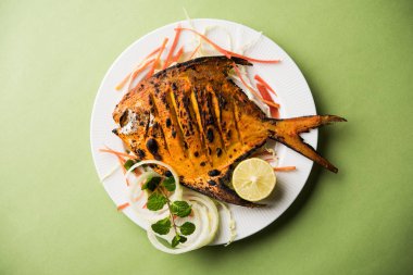 Tandır Pomfret balık kil fırında pişmiş ve limon, nane, lahana ve havuç salatası ile süslenmiş. Seçici odak