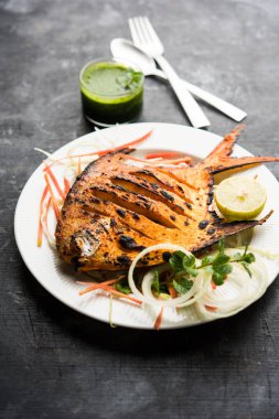 Tandır Pomfret balık kil fırında pişmiş ve limon, nane, lahana ve havuç salatası ile süslenmiş. Seçici odak