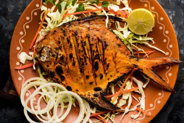 Tandır Pomfret balık kil fırında pişmiş ve limon, nane, lahana ve havuç salatası ile süslenmiş. Seçici odak
