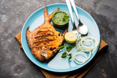 Tandır Pomfret balık kil fırında pişmiş ve limon, nane, lahana ve havuç salatası ile süslenmiş. Seçici odak