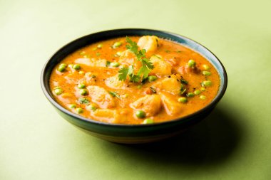 Indian Aloo Mutter curry - Potato and Peas immersed in an Onion Tomato Gravy and garnished with coriander leaves. Served in a Karahi/kadhai or pan or bowl. selective focus clipart