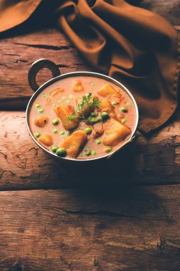 Hint Aloo Mutter köri - patates ve bezelye bir soğan domates et suyu dalmış ve kişniş yaprakları ile süslenmiş. Bir Karahi/kadhai veya pan veya kase servis. seçici odak