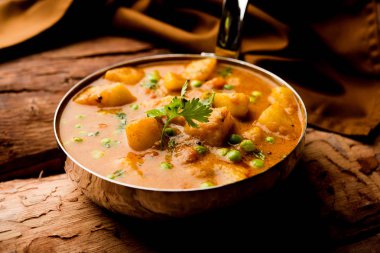 Hint Aloo Mutter köri - patates ve bezelye bir soğan domates et suyu dalmış ve kişniş yaprakları ile süslenmiş. Bir Karahi/kadhai veya pan veya kase servis. seçici odak