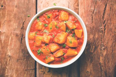 Hint yemeği - Aloo köri masala. Baharatlar ve otlar bir domates köri ile patates pişmiş. bir kapta moody arka plan üzerinde servis. seçici odak