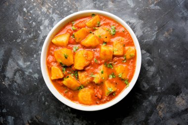 Hint yemeği - Aloo köri masala. Baharatlar ve otlar bir domates köri ile patates pişmiş. bir kapta moody arka plan üzerinde servis. seçici odak