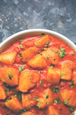 Hint yemeği - Aloo köri masala. Baharatlar ve otlar bir domates köri ile patates pişmiş. bir kapta moody arka plan üzerinde servis. seçici odak