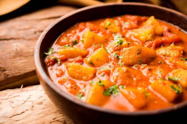 Hint yemeği - Aloo köri masala. Baharatlar ve otlar bir domates köri ile patates pişmiş. bir kapta moody arka plan üzerinde servis. seçici odak