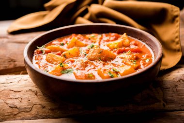 Hint yemeği - Aloo köri masala. Baharatlar ve otlar bir domates köri ile patates pişmiş. bir kapta moody arka plan üzerinde servis. seçici odak