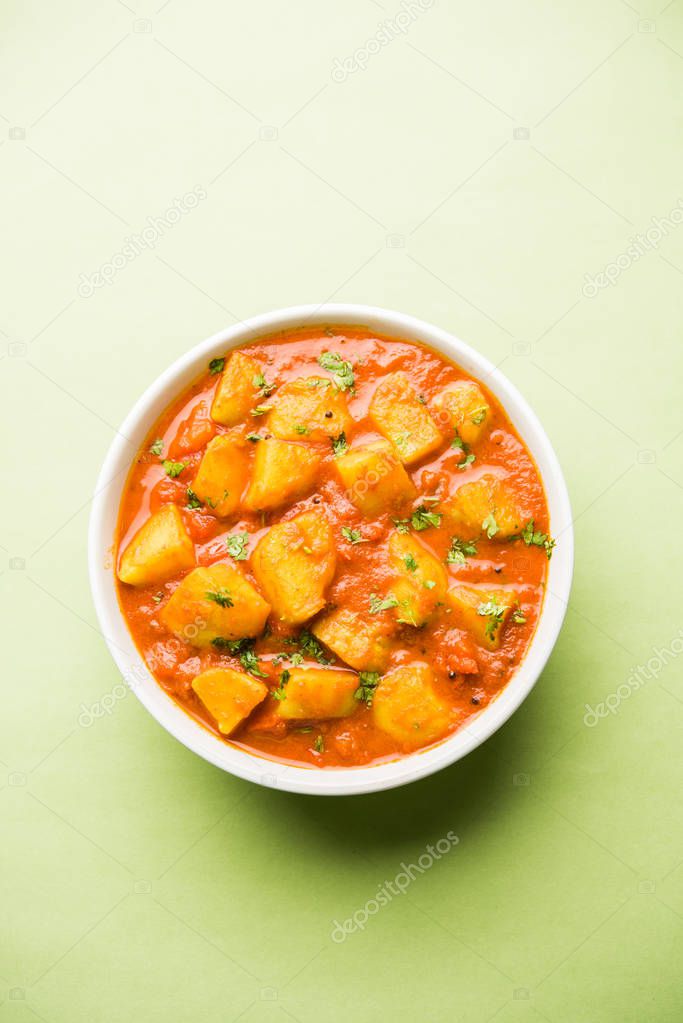 Indian food - Aloo curry masala. Potato cooked with spices and herbs in a tomato curry. served in a bowl over moody background. selective focus