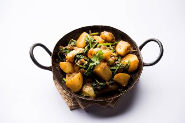 Aloo Palak Sabzi, baharatlı ıspanakla pişirilmiş patates. Sağlıklı bir Hint yemeği tarifi. Bir kasede servis edilmiş, seçici bir odak noktası.