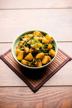 Aloo Palak Sabzi, baharatlı ıspanakla pişirilmiş patates. Sağlıklı bir Hint yemeği tarifi. Bir kasede servis edilmiş, seçici bir odak noktası.