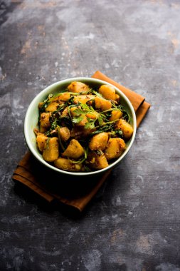 Aloo Palak Sabzi, baharatlı ıspanakla pişirilmiş patates. Sağlıklı bir Hint yemeği tarifi. Bir kasede servis edilmiş, seçici bir odak noktası.