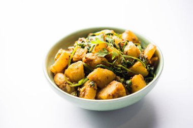 Aloo Palak Sabzi, baharatlı ıspanakla pişirilmiş patates. Sağlıklı bir Hint yemeği tarifi. Bir kasede servis edilmiş, seçici bir odak noktası.