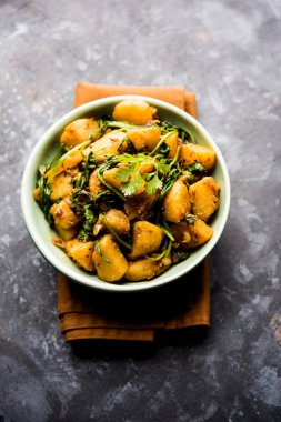 Aloo Palak Sabzi, baharatlı ıspanakla pişirilmiş patates. Sağlıklı bir Hint yemeği tarifi. Bir kasede servis edilmiş, seçici bir odak noktası.