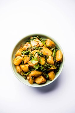 Aloo Palak Sabzi, baharatlı ıspanakla pişirilmiş patates. Sağlıklı bir Hint yemeği tarifi. Bir kasede servis edilmiş, seçici bir odak noktası.