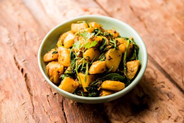 Aloo Palak Sabzi, baharatlı ıspanakla pişirilmiş patates. Sağlıklı bir Hint yemeği tarifi. Bir kasede servis edilmiş, seçici bir odak noktası.