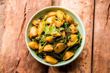 Aloo Palak Sabzi, baharatlı ıspanakla pişirilmiş patates. Sağlıklı bir Hint yemeği tarifi. Bir kasede servis edilmiş, seçici bir odak noktası.