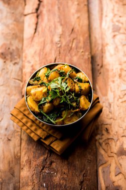 Aloo Palak Sabzi, baharatlı ıspanakla pişirilmiş patates. Sağlıklı bir Hint yemeği tarifi. Bir kasede servis edilmiş, seçici bir odak noktası.