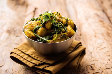 Aloo Palak Sabzi, baharatlı ıspanakla pişirilmiş patates. Sağlıklı bir Hint yemeği tarifi. Bir kasede servis edilmiş, seçici bir odak noktası.