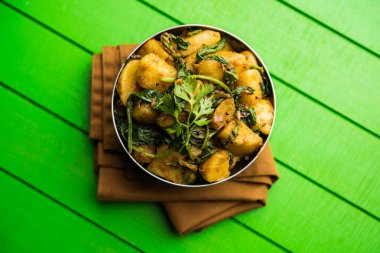 Aloo Palak Sabzi, baharatlı ıspanakla pişirilmiş patates. Sağlıklı bir Hint yemeği tarifi. Bir kasede servis edilmiş, seçici bir odak noktası.