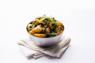 Aloo Palak Sabzi, baharatlı ıspanakla pişirilmiş patates. Sağlıklı bir Hint yemeği tarifi. Bir kasede servis edilmiş, seçici bir odak noktası.