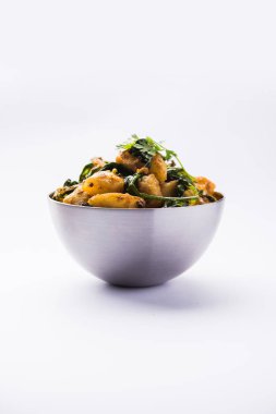 Aloo Palak Sabzi, baharatlı ıspanakla pişirilmiş patates. Sağlıklı bir Hint yemeği tarifi. Bir kasede servis edilmiş, seçici bir odak noktası.