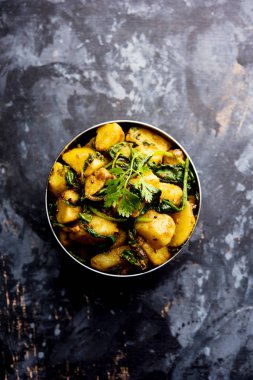 Aloo Palak Sabzi, baharatlı ıspanakla pişirilmiş patates. Sağlıklı bir Hint yemeği tarifi. Bir kasede servis edilmiş, seçici bir odak noktası.