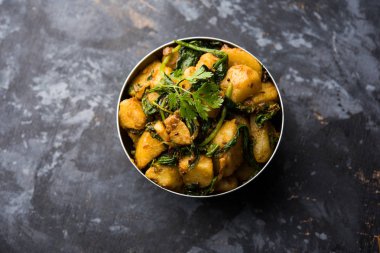 Aloo Palak Sabzi, baharatlı ıspanakla pişirilmiş patates. Sağlıklı bir Hint yemeği tarifi. Bir kasede servis edilmiş, seçici bir odak noktası.