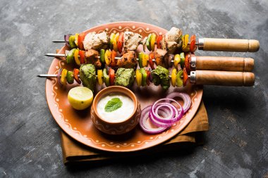 Hariyali kakab tavuk mu Malai malai Kebap tricolour içinde servis ile şiş ve yoğurt dip bir tabak içinde. seçici odak