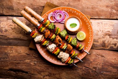 Hariyali kakab tavuk mu Malai malai Kebap tricolour içinde servis ile şiş ve yoğurt dip bir tabak içinde. seçici odak