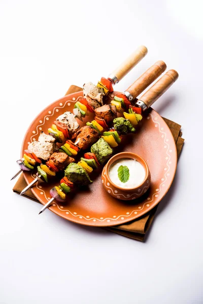 Hariyali kakab tavuk mu Malai malai Kebap tricolour içinde servis ile şiş ve yoğurt dip bir tabak içinde. seçici odak