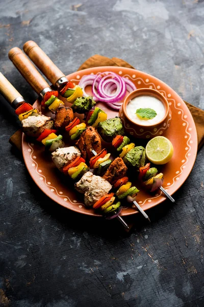 Hariyali kakab tavuk mu Malai malai Kebap tricolour içinde servis ile şiş ve yoğurt dip bir tabak içinde. seçici odak