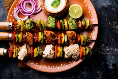 Hariyali kakab tavuk mu ile hizmet Malai malai Kebap şişleri ve yoğurt dip bir tabak içinde. seçici odak