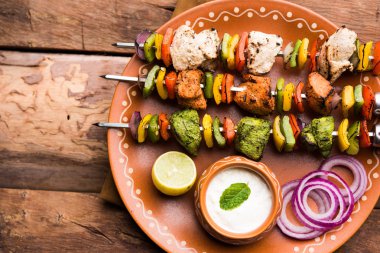 Hariyali kakab tavuk mu ile hizmet Malai malai Kebap şişleri ve yoğurt dip bir tabak içinde. seçici odak