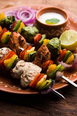 Hariyali kakab tavuk mu ile hizmet Malai malai Kebap şişleri ve yoğurt dip bir tabak içinde. seçici odak
