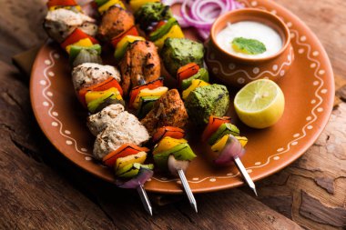 Hariyali kakab tavuk mu ile hizmet Malai malai Kebap şişleri ve yoğurt dip bir tabak içinde. seçici odak