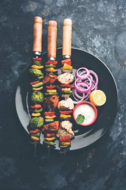 Hariyali kakab tavuk mu ile hizmet Malai malai Kebap şişleri ve yoğurt dip bir tabak içinde. seçici odak