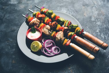 Hariyali kakab tavuk mu ile hizmet Malai malai Kebap şişleri ve yoğurt dip bir tabak içinde. seçici odak