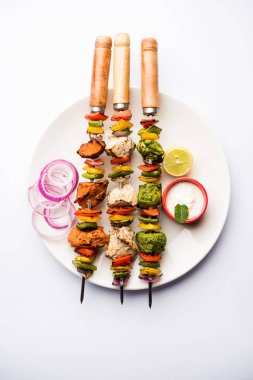 Hariyali kakab tavuk mu ile hizmet Malai malai Kebap şişleri ve yoğurt dip bir tabak içinde. seçici odak