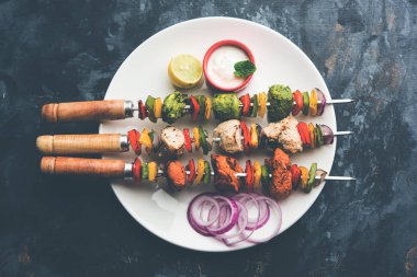 Hariyali kakab tavuk mu ile hizmet Malai malai Kebap şişleri ve yoğurt dip bir tabak içinde. seçici odak