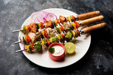 Hariyali kakab tavuk mu ile hizmet Malai malai Kebap şişleri ve yoğurt dip bir tabak içinde. seçici odak