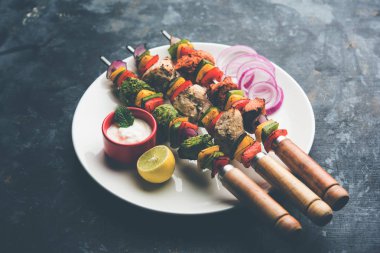 Hariyali kakab tavuk mu ile hizmet Malai malai Kebap şişleri ve yoğurt dip bir tabak içinde. seçici odak