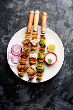 Hariyali kakab tavuk mu ile hizmet Malai malai Kebap şişleri ve yoğurt dip bir tabak içinde. seçici odak