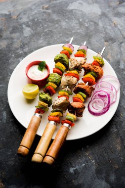 Hariyali kakab tavuk mu ile hizmet Malai malai Kebap şişleri ve yoğurt dip bir tabak içinde. seçici odak