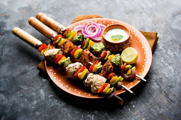 Hariyali kakab tavuk mu ile hizmet Malai malai Kebap şişleri ve yoğurt dip bir tabak içinde. seçici odak