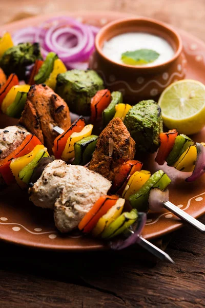 Hariyali kakab tavuk mu ile hizmet Malai malai Kebap şişleri ve yoğurt dip bir tabak içinde. seçici odak